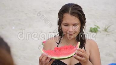 孩子们在海滩上吃西瓜。 青春痘少女吃西瓜慢动作视频生活方式